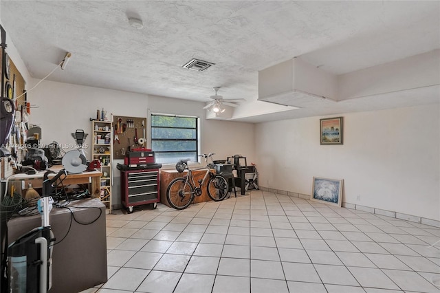 miscellaneous room featuring a workshop area, visible vents, light tile patterned flooring, ceiling fan, and a textured ceiling