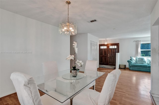 dining space featuring an inviting chandelier, visible vents, and wood finished floors