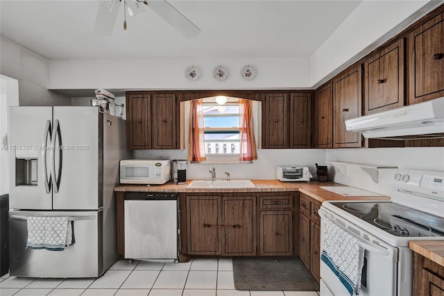 kitchen featuring dark brown cabinetry, appliances with stainless steel finishes, light countertops, under cabinet range hood, and a sink