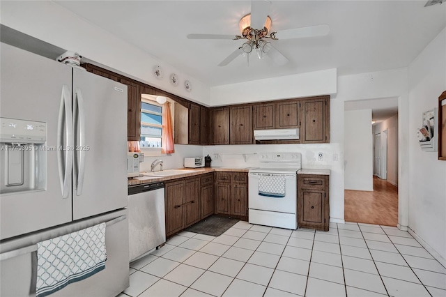 kitchen with light tile patterned floors, light countertops, appliances with stainless steel finishes, a sink, and under cabinet range hood