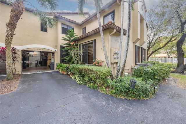 view of property with a garage, aphalt driveway, and fence