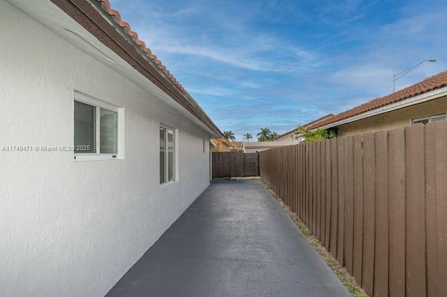 view of side of property featuring a tile roof, fence, and stucco siding