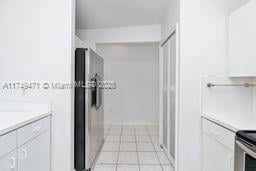 kitchen with stainless steel refrigerator with ice dispenser, light tile patterned floors, white cabinets, and light countertops