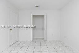 unfurnished bedroom featuring light tile patterned floors, a closet, a walk in closet, and visible vents