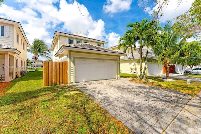 view of front facade featuring a garage, decorative driveway, a front yard, and fence