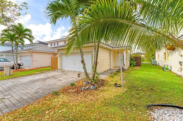 view of side of property featuring a garage, a yard, decorative driveway, and fence