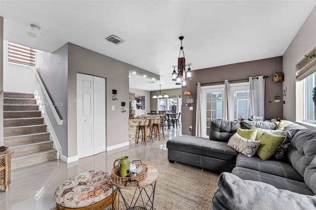 living room featuring stairway, baseboards, visible vents, and tile patterned floors