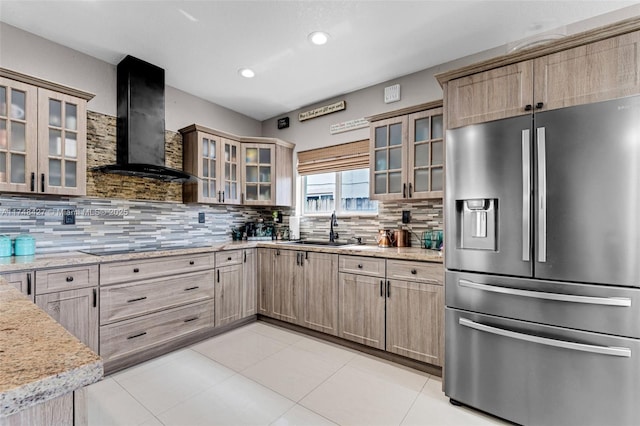 kitchen featuring wall chimney exhaust hood, a sink, glass insert cabinets, and stainless steel fridge with ice dispenser