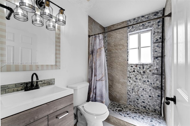 full bathroom with a tile shower, vanity, and toilet