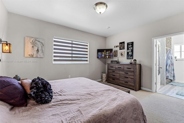 bedroom with light carpet, baseboards, and ensuite bathroom