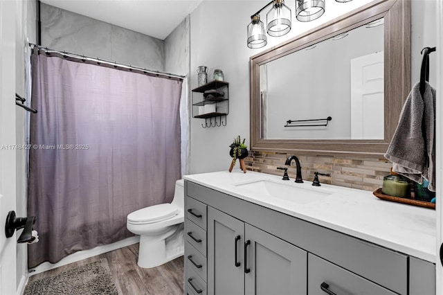 bathroom featuring toilet, wood finished floors, vanity, and decorative backsplash