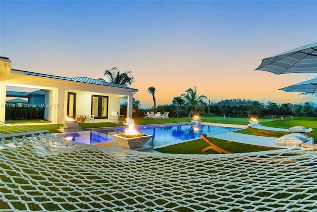 pool at dusk featuring a fire pit, a patio, and an outdoor pool