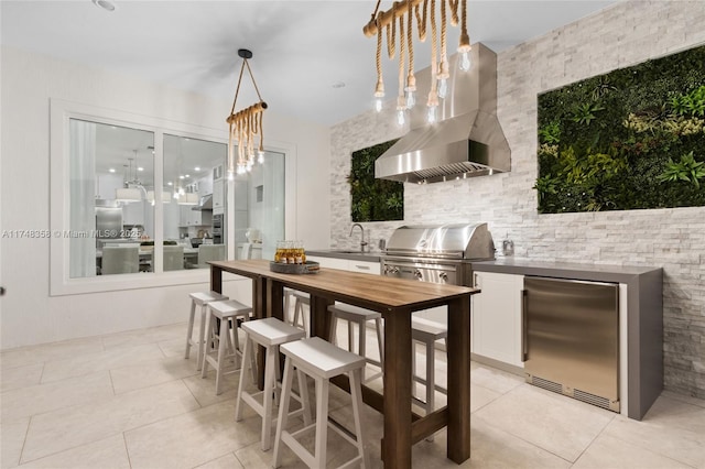 kitchen with pendant lighting, dark countertops, fridge, white cabinets, and exhaust hood