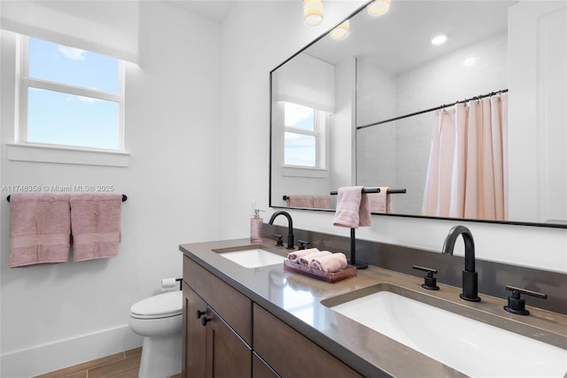 bathroom featuring a shower with shower curtain, a sink, toilet, and double vanity