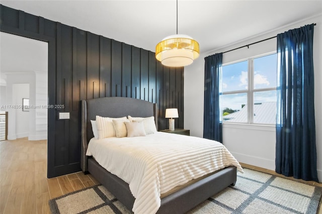 bedroom featuring wooden walls, baseboards, and wood finished floors