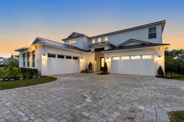 view of front of home with decorative driveway, a standing seam roof, metal roof, and a garage