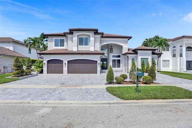 mediterranean / spanish home featuring decorative driveway, an attached garage, and stucco siding