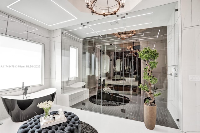 bathroom featuring a stall shower, a chandelier, and a freestanding bath