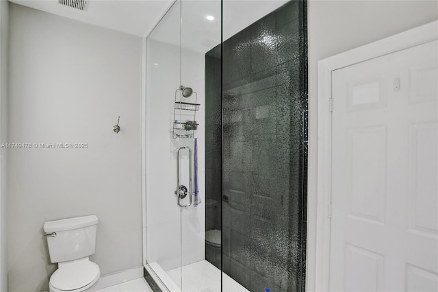 bathroom featuring toilet, a stall shower, and visible vents