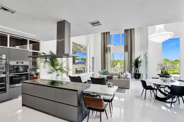 kitchen featuring black electric stovetop, island exhaust hood, visible vents, and gray cabinetry