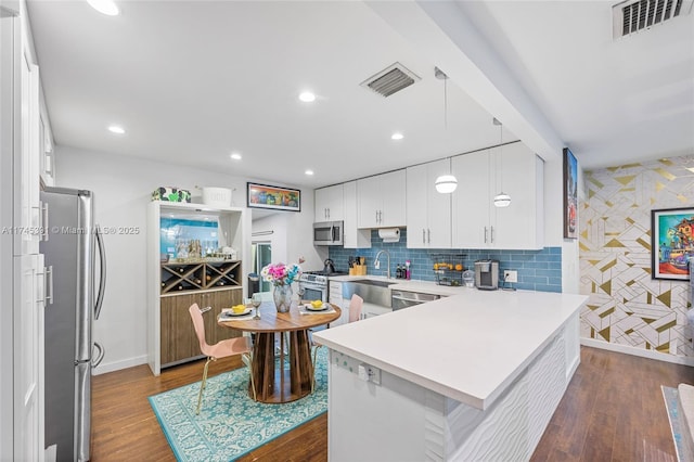 431 NE 110th Ter, Miami, FL 33161 - kitchen featuring appliances with stainless steel finishes, a peninsula, dark wood-style flooring, light countertops, and recessed lighting