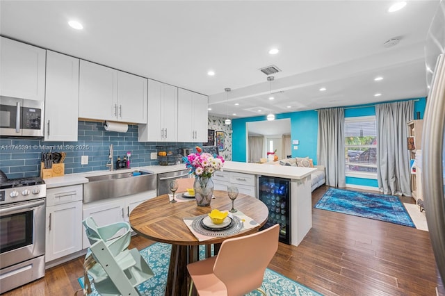 431 NE 110th Ter, Miami, FL 33161 - kitchen featuring beverage cooler, appliances with stainless steel finishes, a peninsula, light countertops, and white cabinets