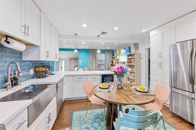 431 NE 110th Ter, Miami, FL 33161 - kitchen featuring stainless steel appliances, a peninsula, white cabinetry, decorative backsplash, and light countertops