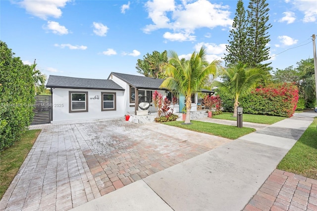 431 NE 110th Ter, Miami, FL 33161 - ranch-style home featuring stucco siding, decorative driveway, a front lawn, and a shingled roof
