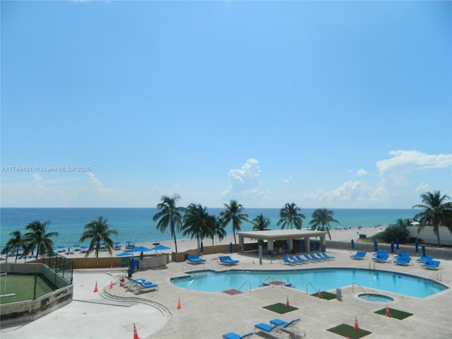 pool with a water view, a patio area, fence, and a community hot tub