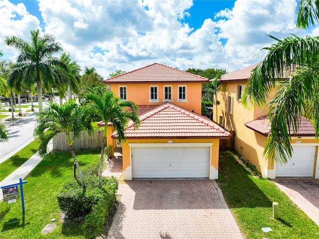 mediterranean / spanish home with decorative driveway, a tile roof, stucco siding, fence, and a garage