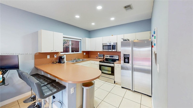 kitchen with appliances with stainless steel finishes, light countertops, white cabinets, and visible vents