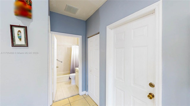 hallway with light tile patterned floors, visible vents, and baseboards