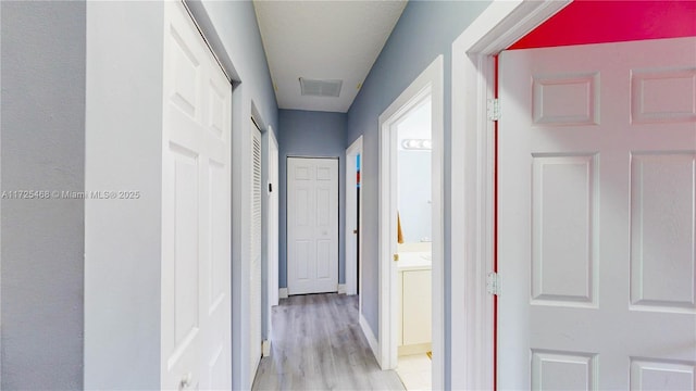 corridor with light wood finished floors and visible vents