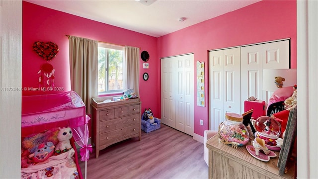 bedroom featuring wood finished floors and two closets
