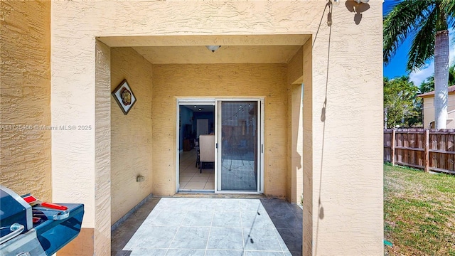 entrance to property with fence and stucco siding