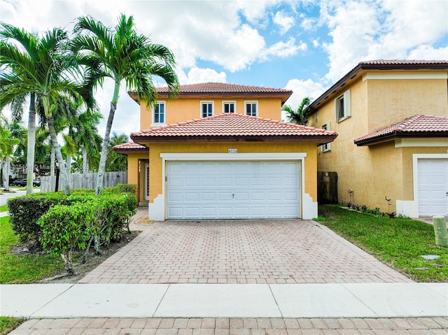 mediterranean / spanish house with decorative driveway, fence, an attached garage, and stucco siding