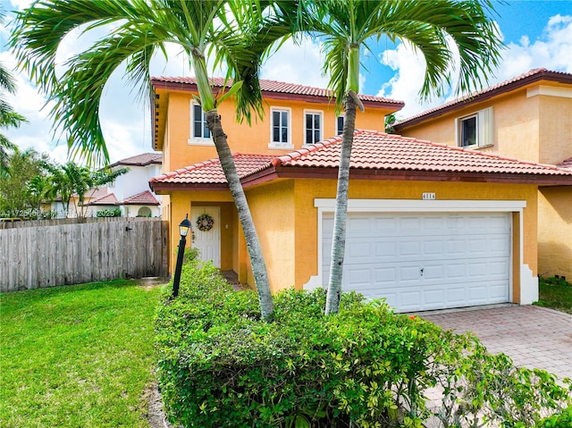 mediterranean / spanish home with a garage, a front yard, fence, and stucco siding