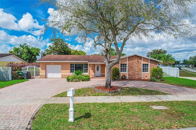 view of front of house with decorative driveway, stucco siding, a front yard, fence, and stone siding