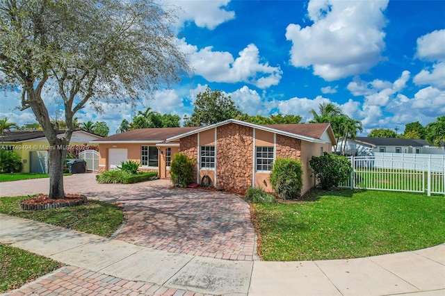 view of front of house with decorative driveway, stone siding, fence, and a front lawn