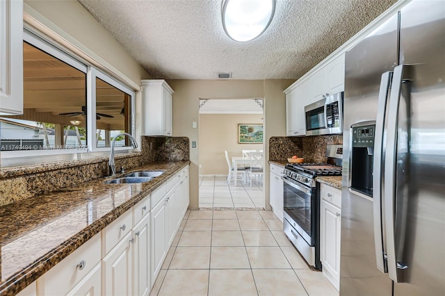 kitchen with light tile patterned floors, a sink, visible vents, white cabinetry, and appliances with stainless steel finishes