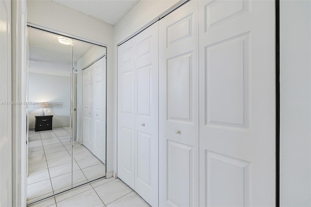 hallway featuring a textured ceiling and light tile patterned floors