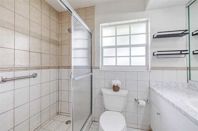 bathroom featuring tile walls, a shower stall, toilet, and vanity