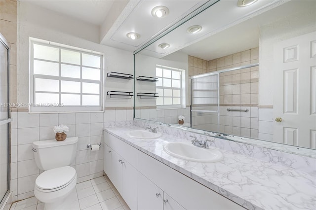 bathroom featuring a stall shower, a sink, and tile walls