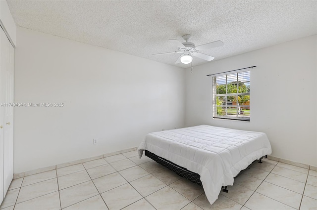 bedroom featuring a textured ceiling, light tile patterned flooring, and a ceiling fan