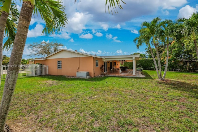 back of house with a lawn, ceiling fan, fence, a patio area, and stucco siding