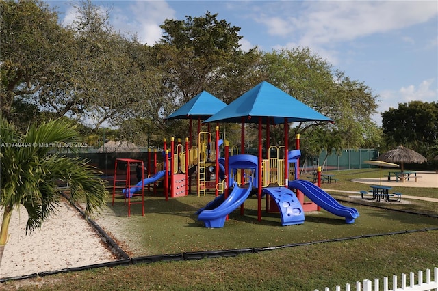 communal playground featuring a yard and fence