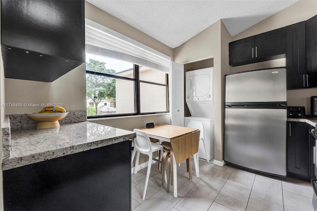 123 NW 98th Ter, Plantation, FL 33324 - kitchen featuring lofted ceiling, dark cabinets, freestanding refrigerator, a textured ceiling, and stacked washing maching and dryer