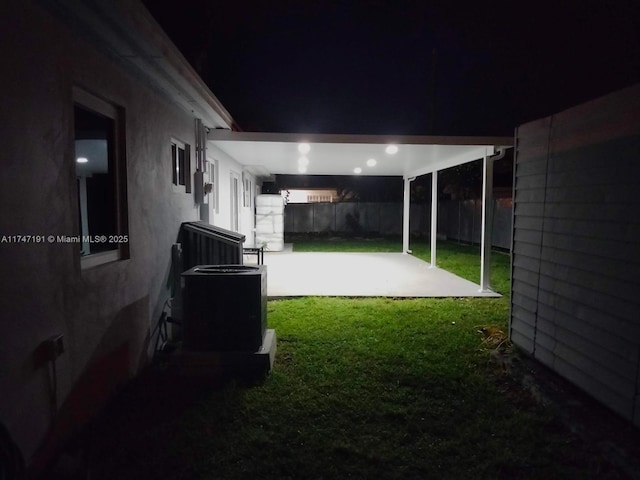 yard at twilight featuring a patio, fence, and central air condition unit
