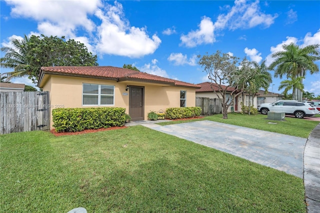 view of front of property with a tile roof, a front yard, fence, and stucco siding