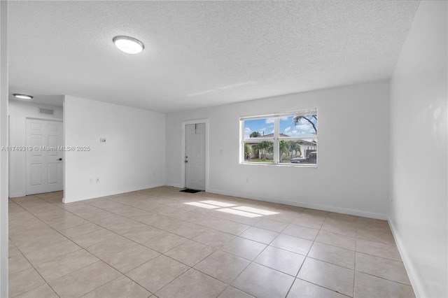 unfurnished room with visible vents, a textured ceiling, baseboards, and light tile patterned floors